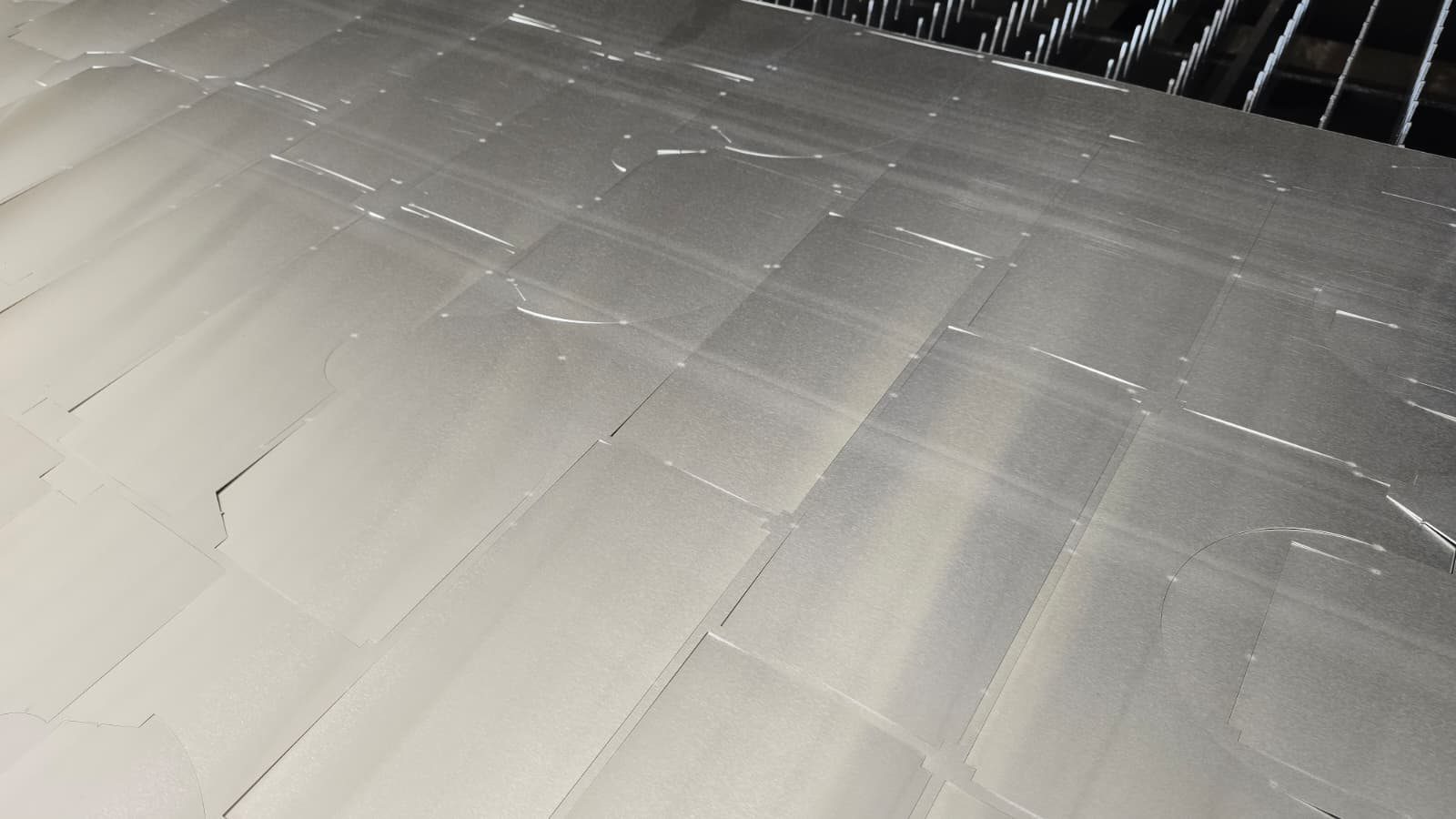 Geschnittene Aluminiumtafel auf dem Maschinentisch: die Ummantelungsteile hängen über Mikrostege in der Tafel